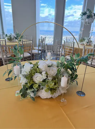 Floral centerpiece with candles under a gold hoop on a table